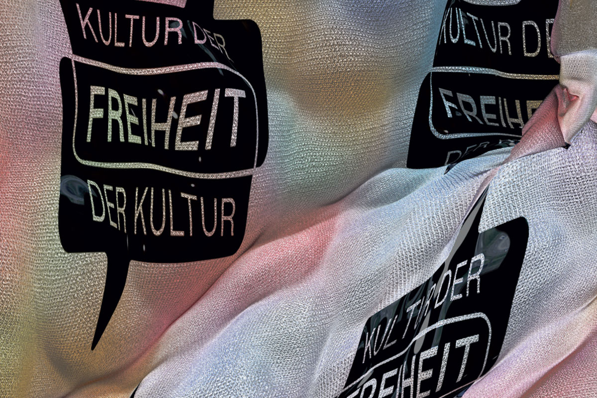 Das Foto zeigt bewegten Stoff, auf dem mehrfach der Text Kultur der Freiheit der Kultur zu lesen ist