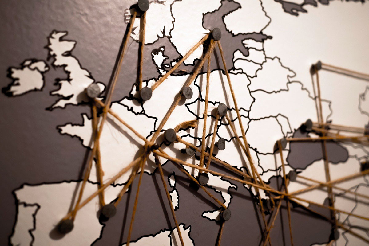Ein Netz aus braunen Fäden spannt sich über eine gezeichnete Europakarte